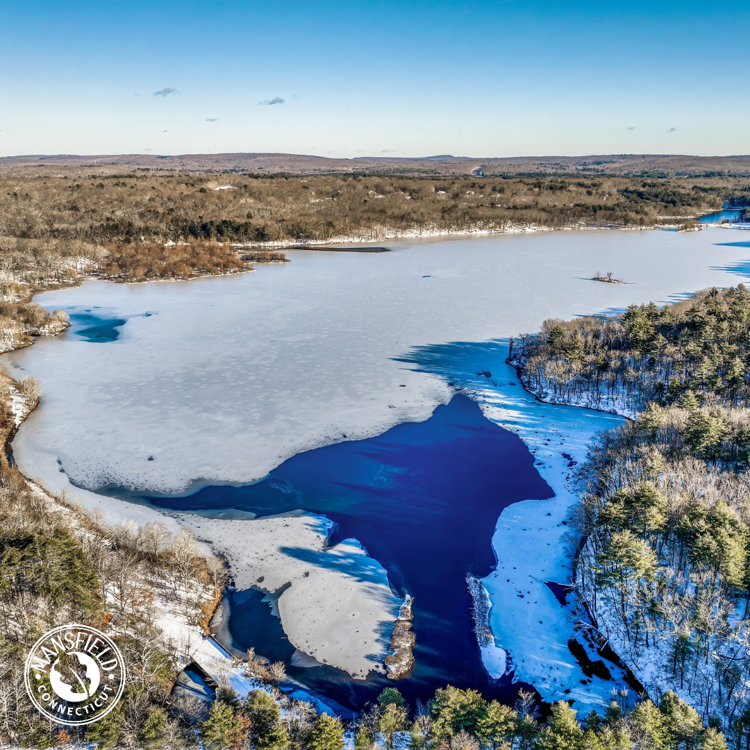 Aerial view of Mansfield Hollow Lake in winter, snow and ice cover most of the water